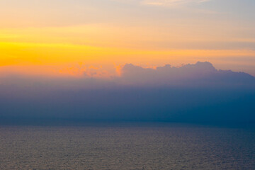 Fototapeta premium Enjoy the panoramic view of the horizon, the sunrise with colorful clouds and beautiful cloud patterns in the soft morning light, contrasting with the golden reflection of the sea.