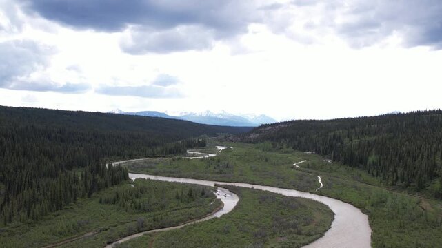 4K, 59.94fps. Mid-altitude aerial following the winding S-curves of the Little Nelchina River near Eureka, Alaska, flying toward majestic snow-capped mountains.