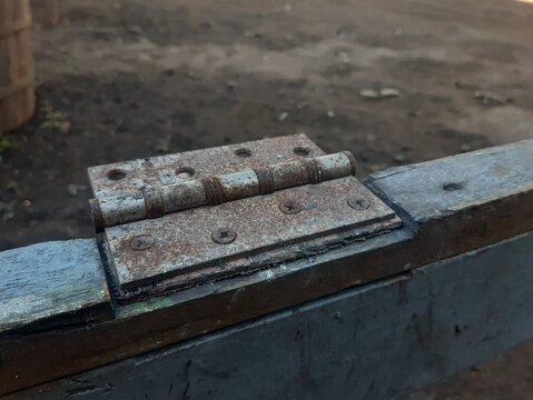 close-up of rusty metal door hinge on weathered wooden frame
