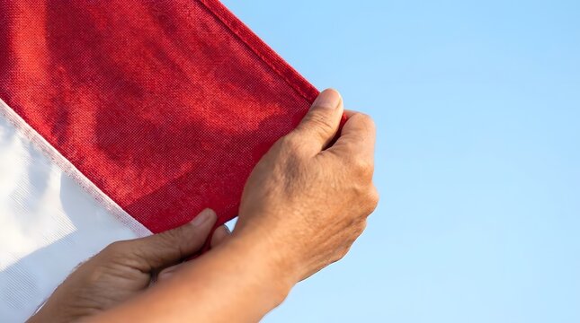 Hands holding red and white Indonesian flag.