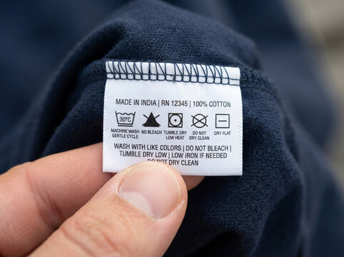 Clothing care label on cotton fabric. Garment washing instructions tag for textile laundry.