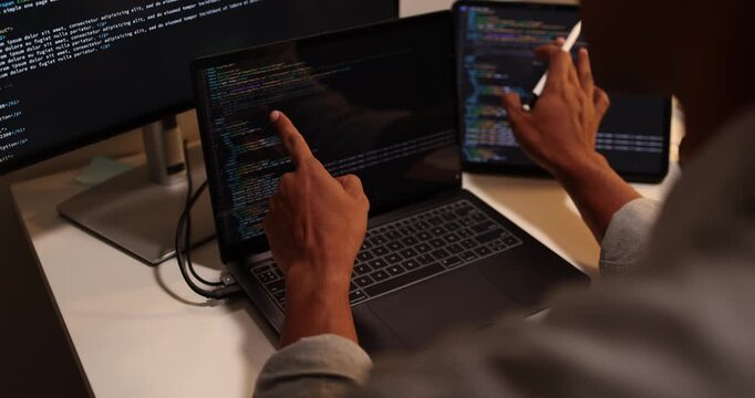 Software developer writing, reviewing and debugging source code across multiple screens using tablet and computer in modern workspace for software engineering, programming and application development.