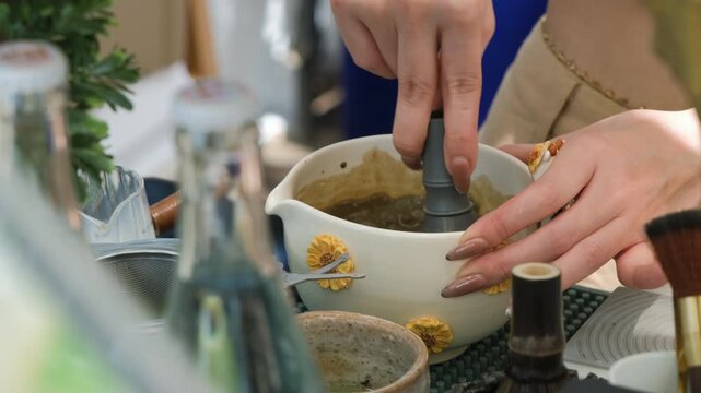 Close-up of a female vendor vigorously whisking matcha powder mixture with a traditional bamboo whisk at a Thai outdoor street market. Matcha preparation concept