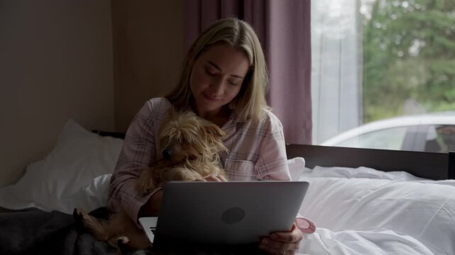 Enjoying time with a pet while using a laptop in a cozy room during the day