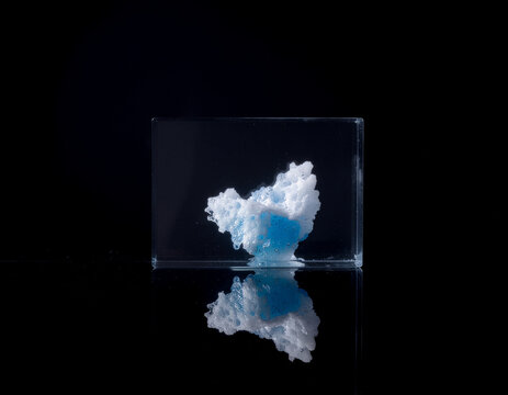 conceptual image of an ancient glacier preserved inside a crystal-clear glass cube on a dark reflective surface