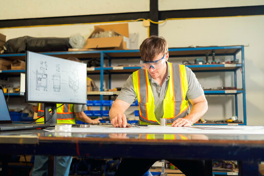 Industrial engineer reviewing technical blueprints in a factory workshop.