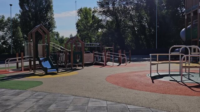 Modern empty children playground with wooden playhouses and merry-go-round.