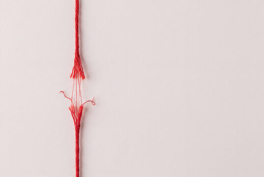 Breaking point concept, a red thread frayed and coming apart under stress, burnout and exhaustion, with copy space