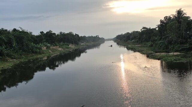 ​Scenic Rural Canal Surrounded By Green Trees Used For Jute Retting At Sunset