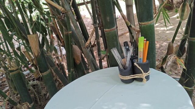 Handcrafted Bamboo Pen Holders on Table with Bamboo Stalks Background