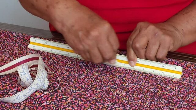 Woman Hands Using Ruler and Chalk to Measure Patterned Fabric