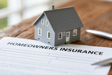 Fototapeta premium Model house on homeowners insurance document with pen, symbolizing property protection and financial security.