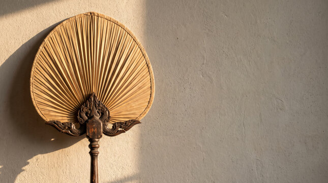 Traditional Thai Palm Leaf Ceremonial Fan on a Plaster Wall