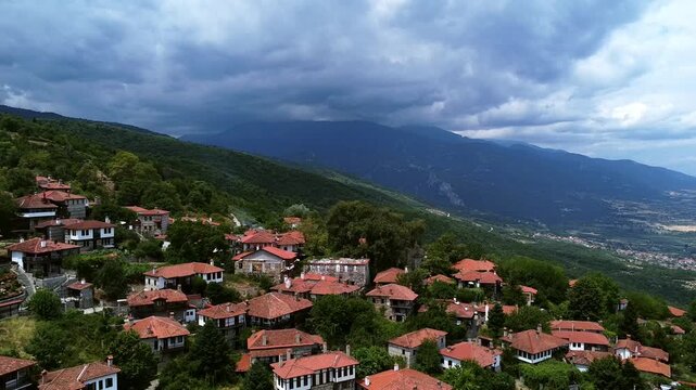 Aerial view of a traditional mountain village with red roofs and majestic Mount Olympus in the background