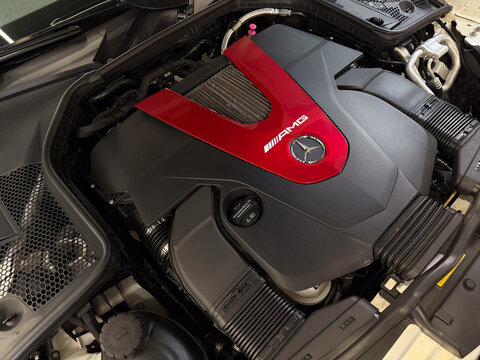 Close-up of a modern Mercedes-AMG 43 BiTurbo V6 petrol engine. High performance 3.0-liter twin-turbocharged M276 engine with iconic red V-shaped plastic cover and brand logo under the car hood.