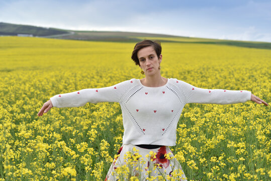 Woman wearing white knit sweater with red embroidery in a field