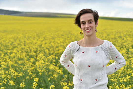 Woman wearing white knit sweater with red embroidery in a field