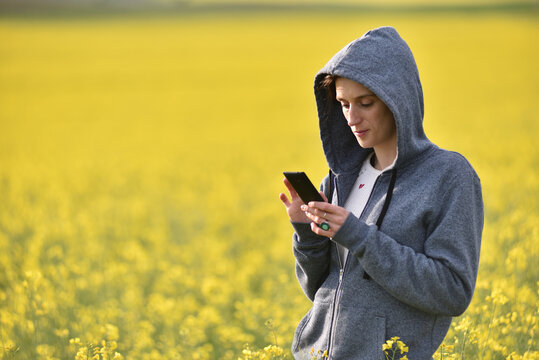 Woman in a gray hoodie using her phone outdoors