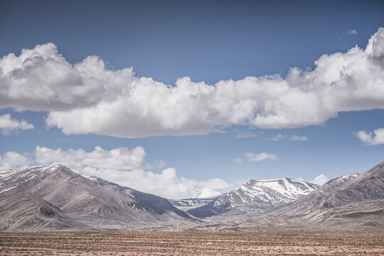 A desert landscape in the highlands of the Pamirs on a sunny summer day with mountains, peaks, and ridges of the Tien Shan mountain range