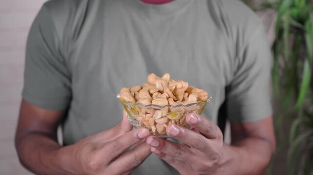 Hand holding a bowl of cashew nuts in a kitchen