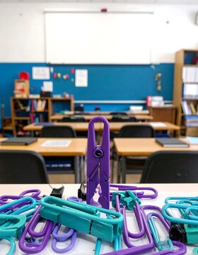 Purple and teal plastic laundry clothespins on a classroom desk.