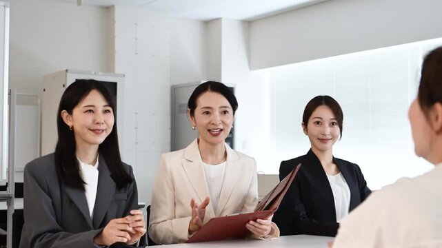 会議で笑顔を見せながら打ち合わせをする20代から40代の日本人ビジネスパーソン4人