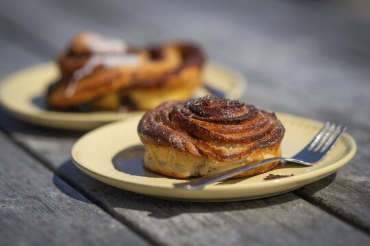 Cinnamon roll and fork lie on a light yellow plate, Houvig, Ringk&oslash;bing Fjord, Denmark