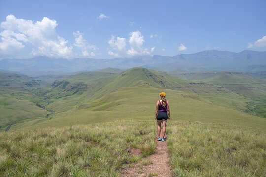 Green hills and valleys, young woman hiking through landscape, Worlds View Hike, Drakensberg, South Africa