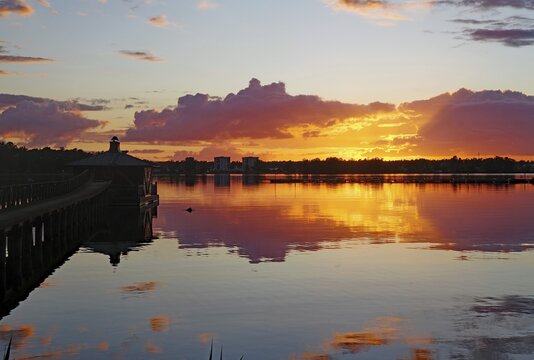 The sky glows orange and purple at sunset with clouds and reflections on the still water surface, G&ouml;ta Canal, Karlsborg, V&auml;stra G&ouml;talands l&auml;n, Sweden