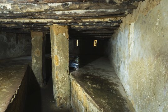 Interior of an underground slave holding chamber in Stone Town, Zanzibar. Low-angle view of cramped stone platforms and narrow air slits in a somber historic site