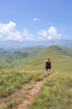 Green hills and valleys, young woman hiking through landscape, Worlds View Hike, Drakensberg, South Africa