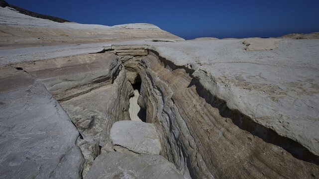 Erosion cracks in dry rock under clear blue sky, white volcanic strata, bizarre white rocks in the sea, Little Sarakiniko, Kioni Beach, Kioni, Kimolos Island, Cyclades, Greek Islands, Greece