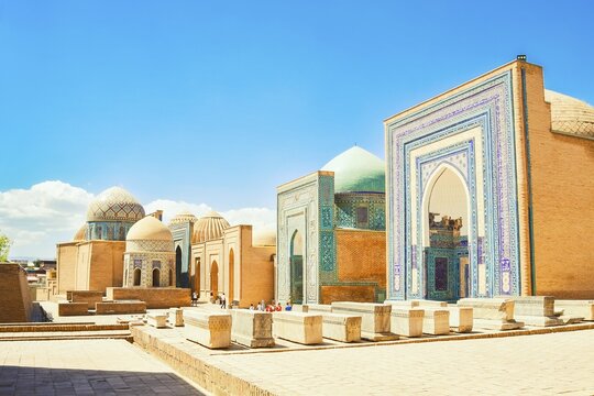 Shah i Zinda necropolis in Samarkand. Visitors explore the stunning blue-tiled mausoleums and turquoise domes of historic UNESCO Silk Road landmark