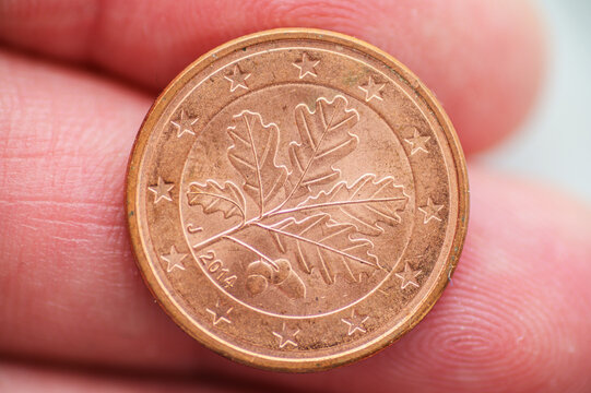 Close-up of a one euro cent coin with oak leaf design held between fingers