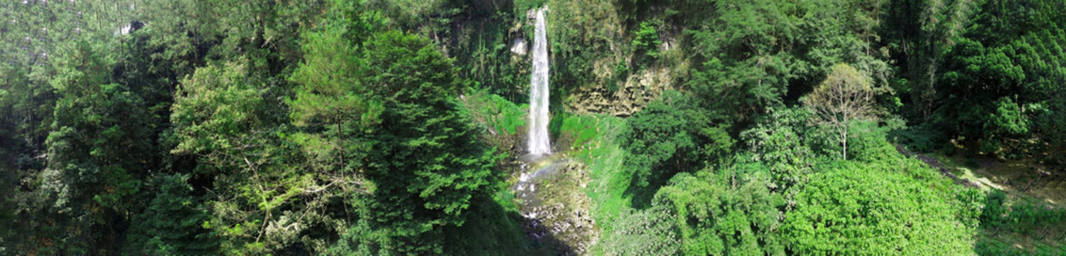 Panoramic Waterfall of grojokan sewu in Indonesia streaming down, cascades down steep, verdant cliffside, through dense jungle. Ideal for travel , nature promos, and tourism features