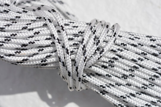Close up view of a coiled white synthetic rope with black tracer lines