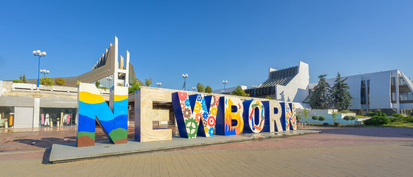 Pristina, Kosovo - June 28, 2026: The iconic NEWBORN monument on Bill Clinton Boulevard with the National Library of Kosovo in the background during an early summer morning in Pristina, Kosovo.