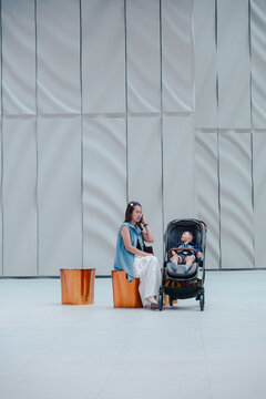 Asian family mother and child with baby carriage in modern shopping mall hall.