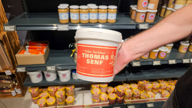 Hand holding thomas senf mustard bucket in supermarket