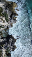 Fototapeta premium Cinematic view of turquoise Caribbean ocean waves crashing against the rocky cliffs of Isla Mujeres, Mexico