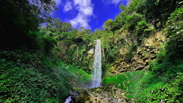 Waterfall of grojokan sewu in Indonesia streaming down, cascades down steep, verdant cliffside, through dense jungle. Ideal for travel , nature promos, and tourism features