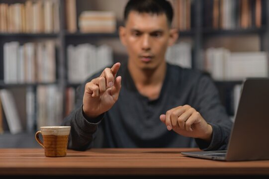 Man in casual clothing using finger gesture at desk in home office setting