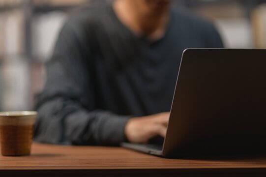 Modern man working on a sleek laptop at wooden desk in bright office setting