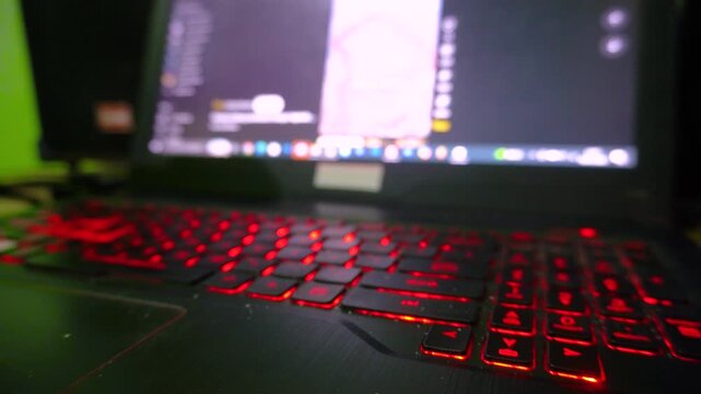 A person scrolling through social media feeds on a laptop computer with glowing red backlit keyboard keys, capturing modern online browsing habits and digital lifestyle trends.