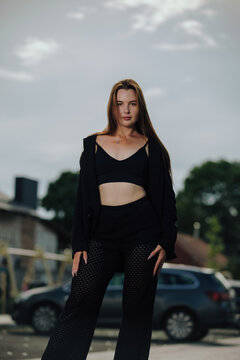 Elegant female in black blazer and crop top posing on urban background