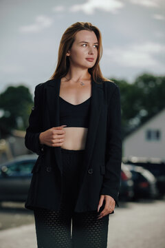 Elegant woman in black blazer looking away posing outdoors with flash lighting