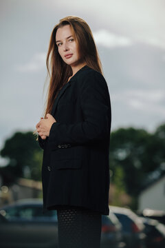 Beautiful woman in black blazer looking at camera in three quarter view outdoors