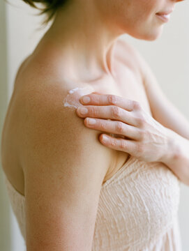 Aloe vera lotion on shoulder treats sunburn skin in soft daylight, hand applying cooling cream on collarbone, clean natural wellness closeup