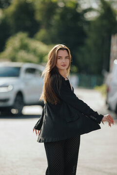 Dynamic portrait of woman spinning around in black blazer outdoors