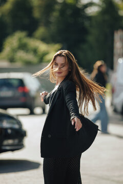 Dynamic portrait of woman spinning around in black blazer outdoors